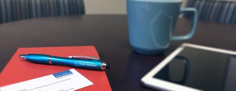 Folder and pen next to coffee and tablet